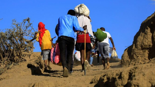 Ethiopians, who fled the ongoing fighting in Tigray region, carry their belongings after crossing the Setit River on the Sudan-Ethiopia border, in the eastern Kassala state, Sudan December 16, 2020. REUTERS/Mohamed Nureldin Abdallah